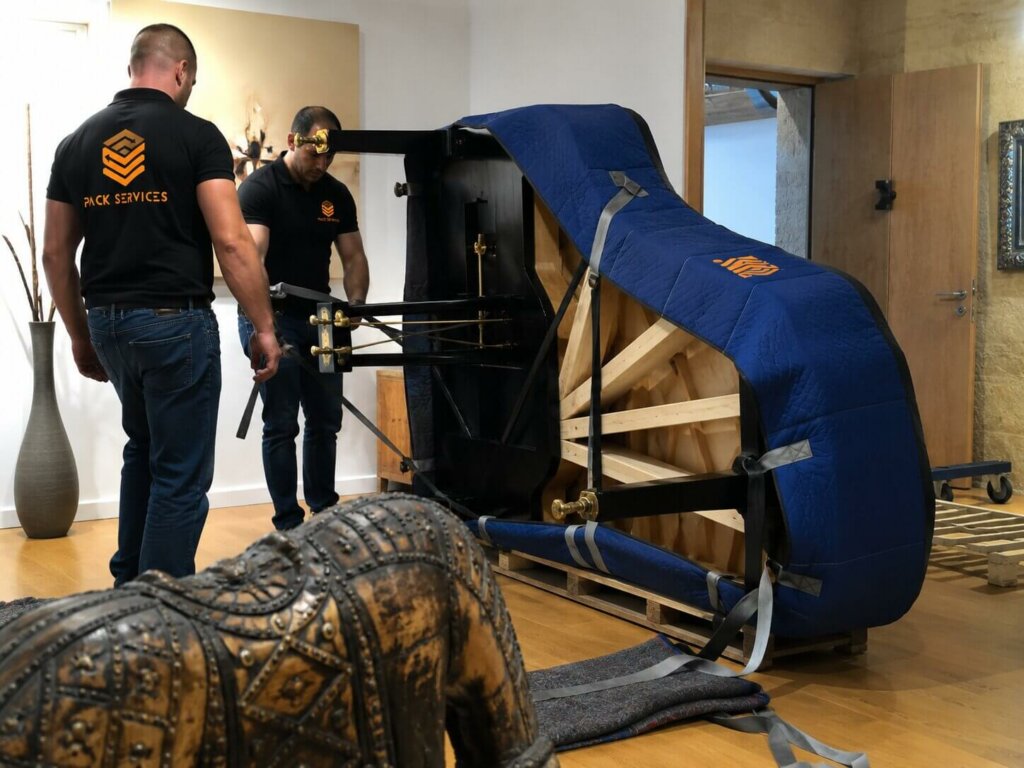 Déménageurs professionnels de Pack Services transportant un piano à queue à Paris tout en le protégeant avec une housse de protection
